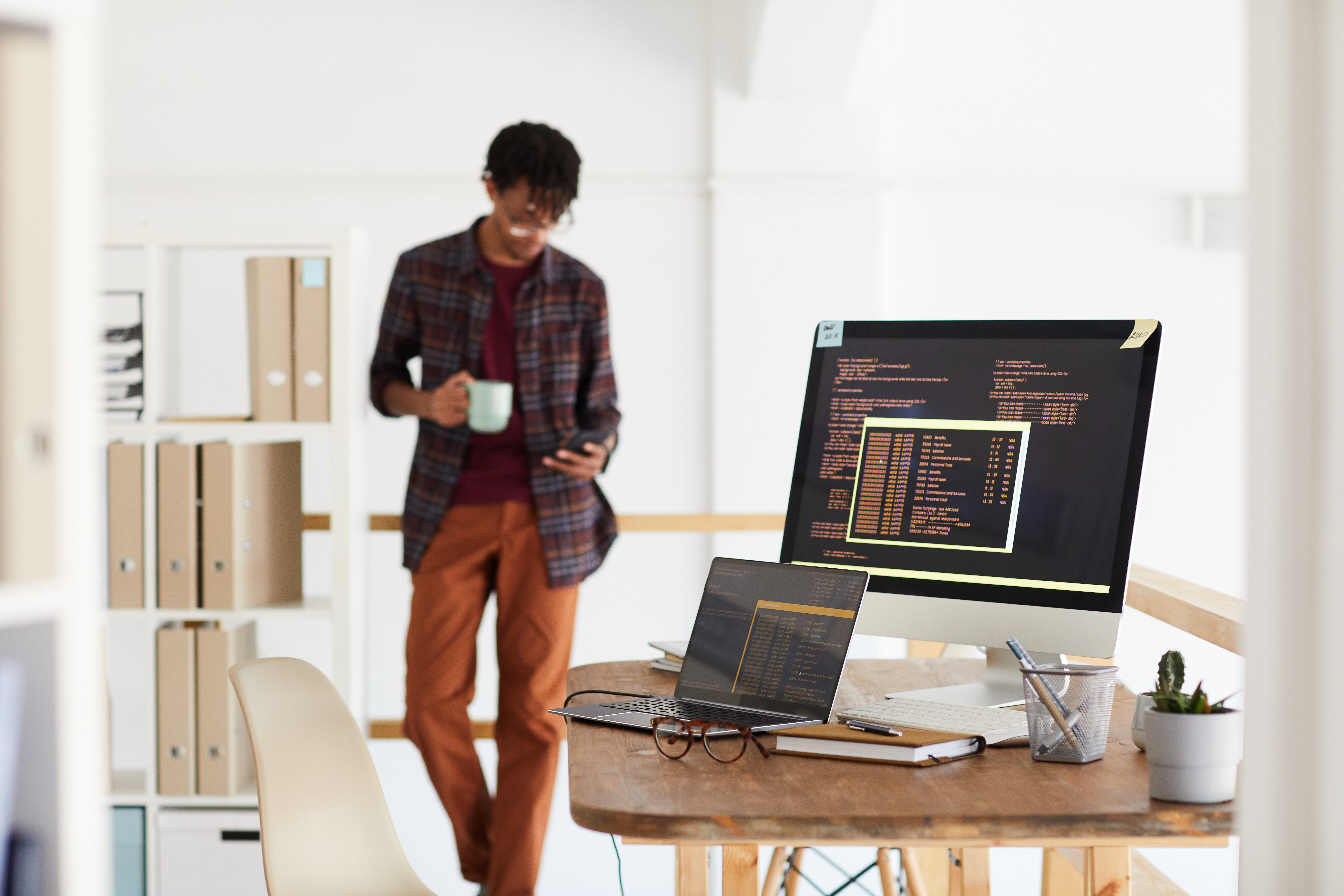 background-image-of-programming-code-on-computer-screen-in-modern-office-interior-with-blurred-shape-of-african-american-man-copy-space